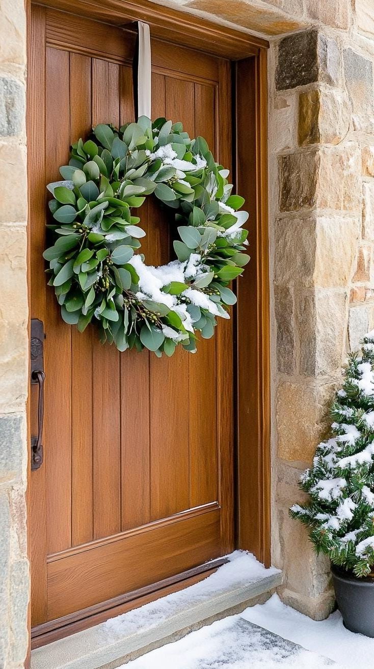 15 Gorgeous Winter Porch Decor Ideas to Spark Your Creativity 21 7. Snow-Dusted Eucalyptus Wreath on Wooden Door-0