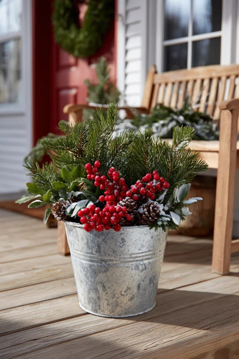 31 Cozy Rustic Decor Ideas for a Warm Xmas 45 outdoor galvanized bucket overflowing with pine boughs and red berries 1