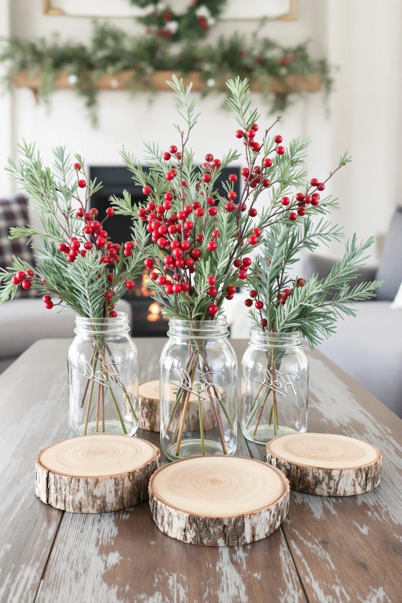 31 Cozy Rustic Decor Ideas for a Warm Xmas 16 mason jar vases holding red berries, cedar sprigs, and wood slices 1